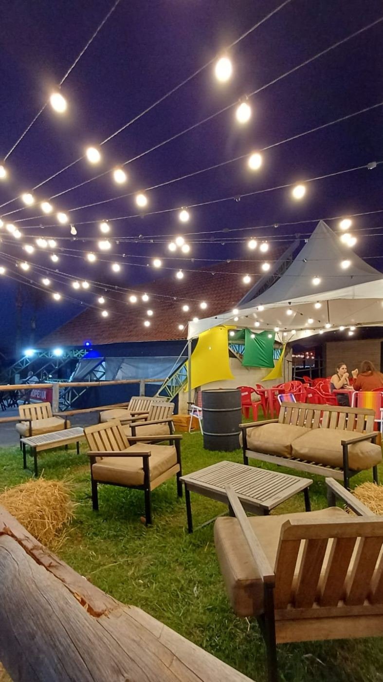 Lounge com sofás de madeira e varal de luzes à noite