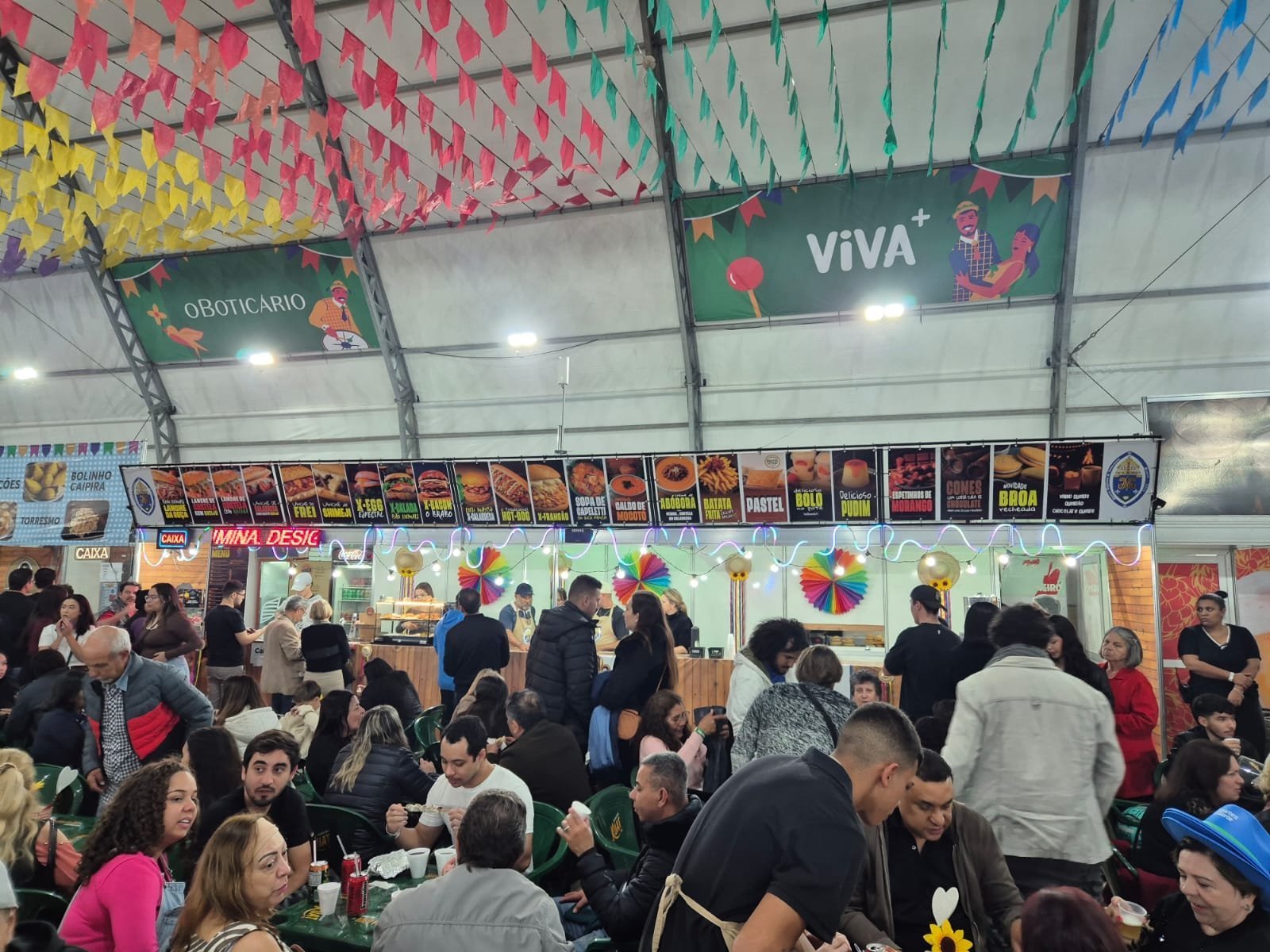 Público lotando as mesas em frente às barracas